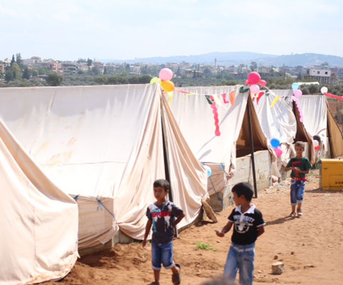 Petits garçons courent dans un camps de réfugiés syriens.