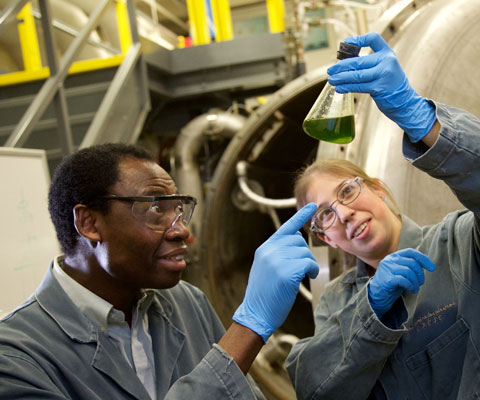 Two researchers looking at a flask of liquid in a lab.