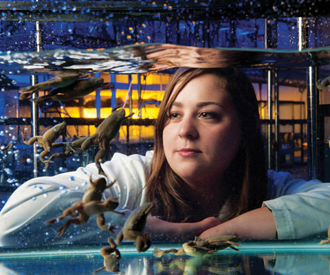 Female student looking at a tank of frogs.
