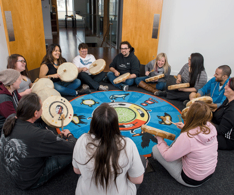Students siting in circle with drums 