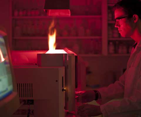 Un chercheur regarde une flamme dans un laboratoire sombre.