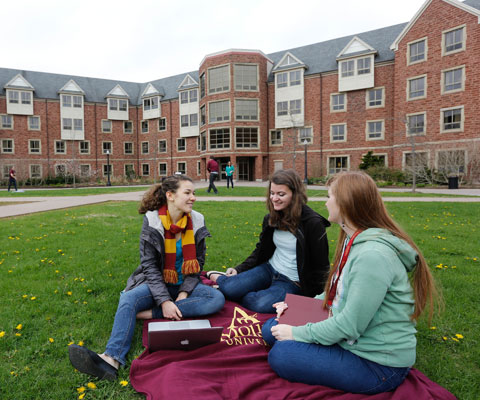 3 females sitting on the garden of Mount Allison University