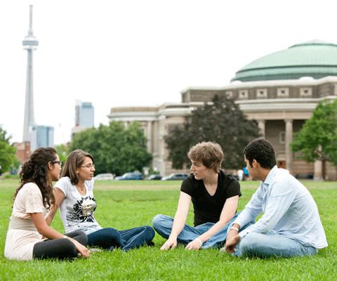 2 female and 2 male students sitting on grass 