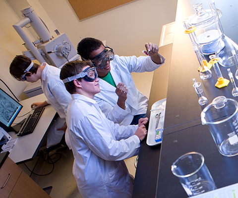 Students working on laboratory wearing white suit and eye protector glass 