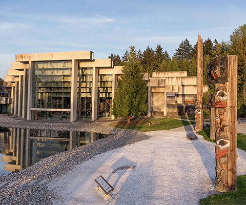 Modern building with totem poles around it