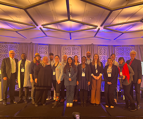 A group of graduate students and university presidents standing together on stage at Accelerate 2023.