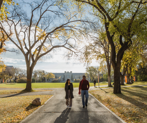 Two students walking through campus in fall