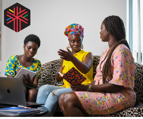 Three African women sitting together in discussion . Holding laptop and notebooks.