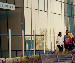 Three student standing outside a research complex building on a university campus.