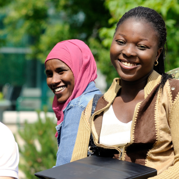 A group of four students sitting outside, smiling.