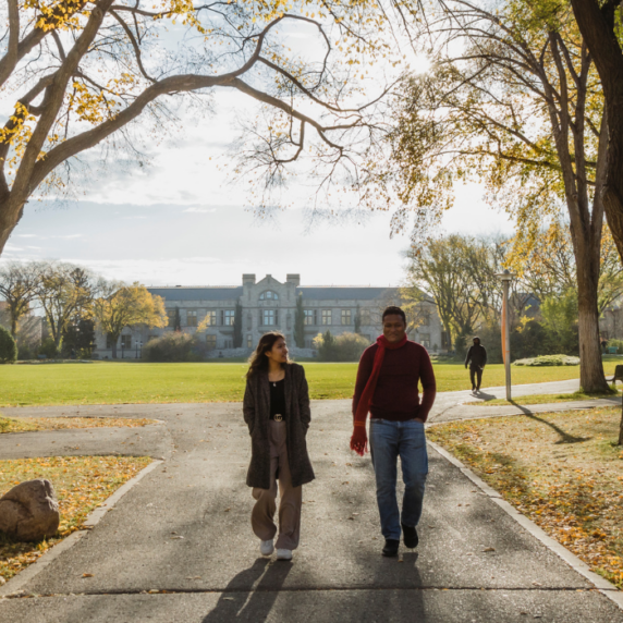 Two students walking through campus in fall