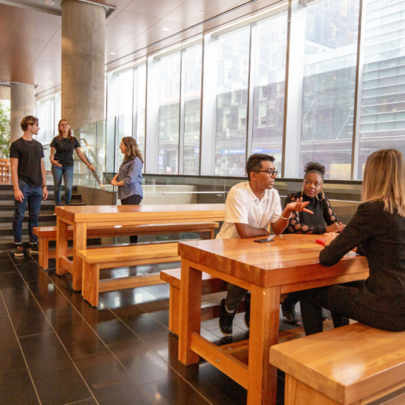 Four students sitting on a bench and three students standing talking