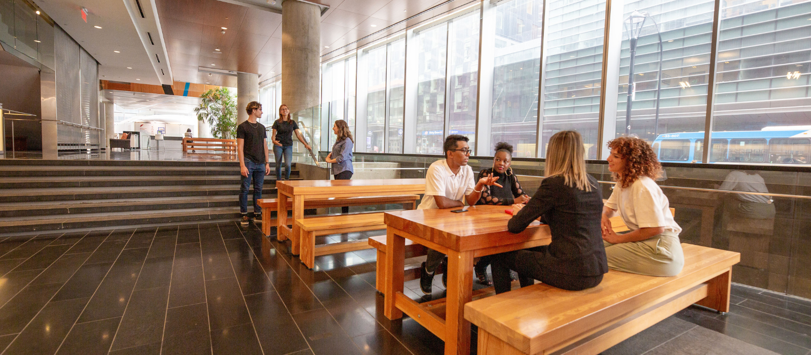 Four students sitting on a bench and three students standing talking