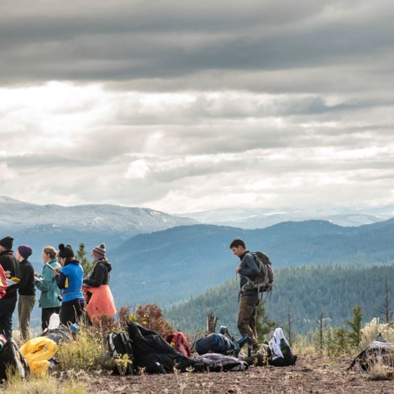 Student researchers on a mountain testing soil on a cloudy day