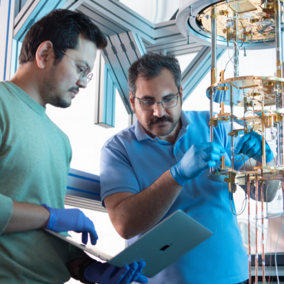 Two men working in a lab with a computer and machinery