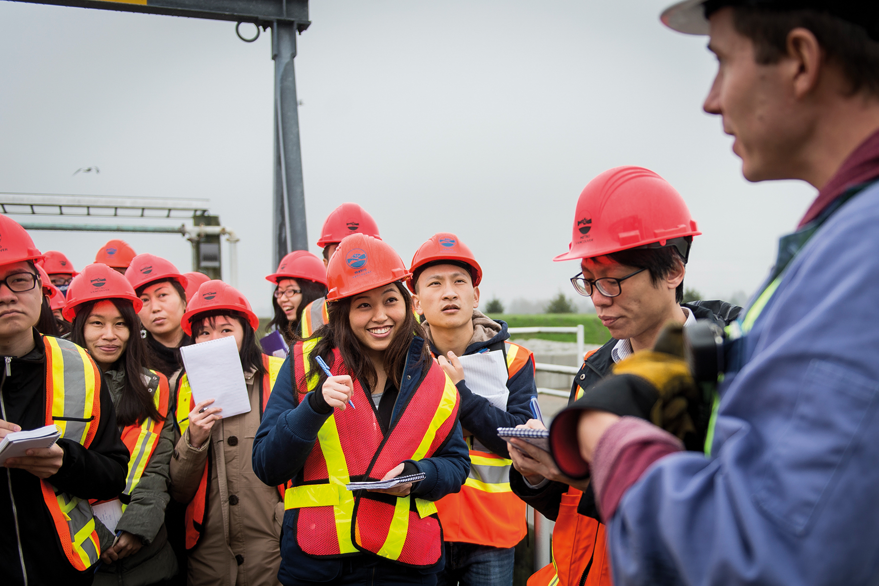 Des étudiants équipés de casques de chantier et de gilets de sécurité suivent une formation sur le terrain.