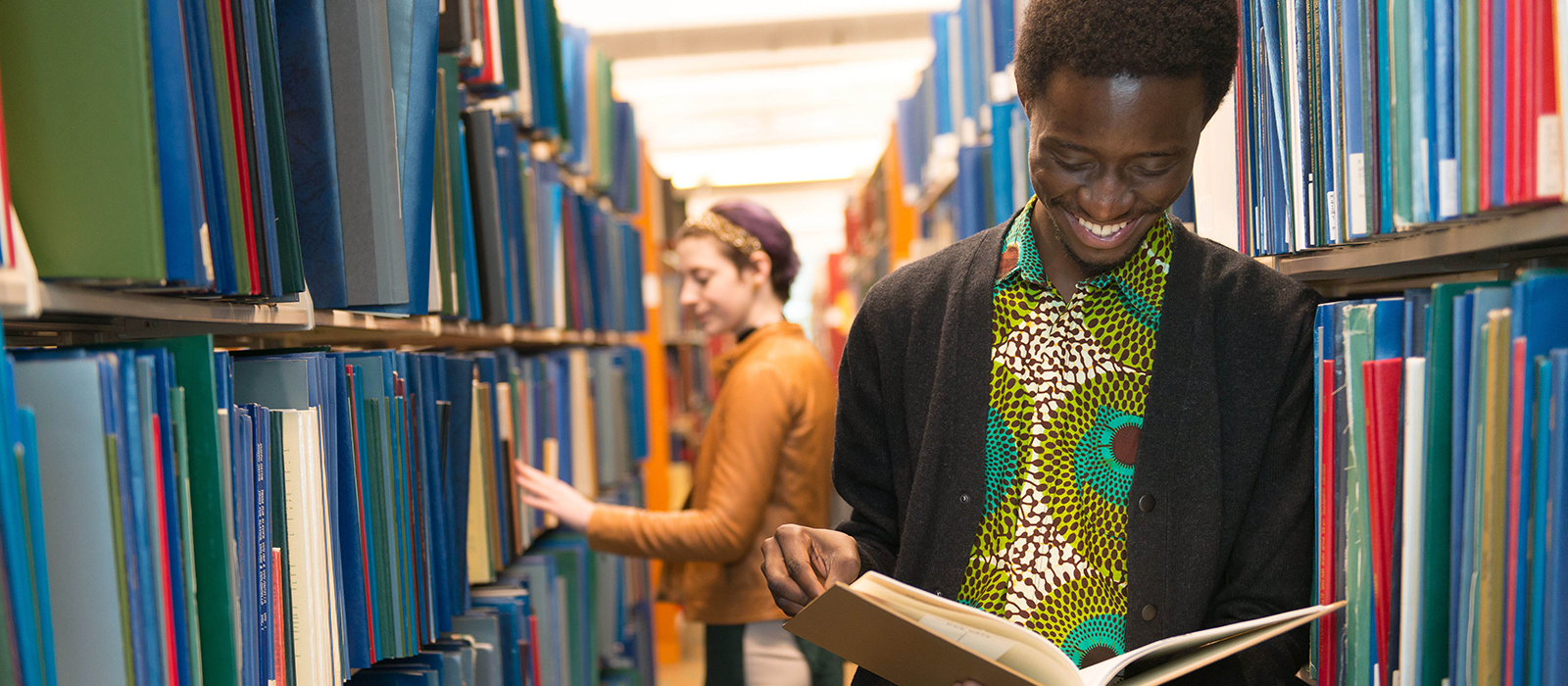 Two students in library looking at books