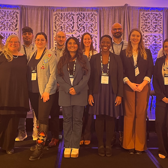 A group of graduate students and university presidents standing together on stage at Accelerate 2023.