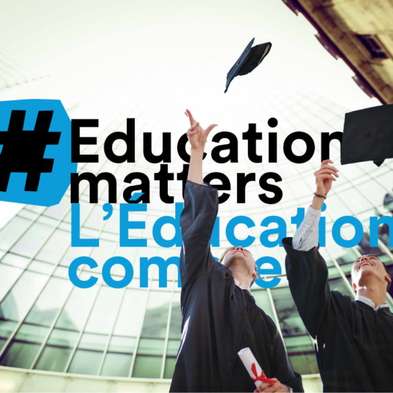 Graduates throw cap in front of skyscrapers