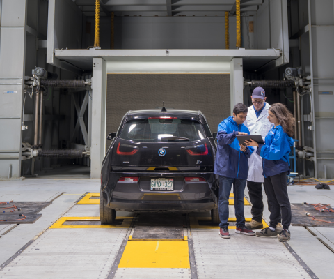 Students with a teacher in a mechanical lab with a car