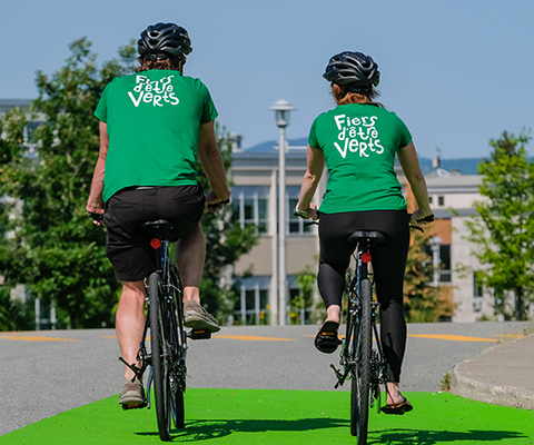 Backs of two people wearing matching green shirts on bicycles