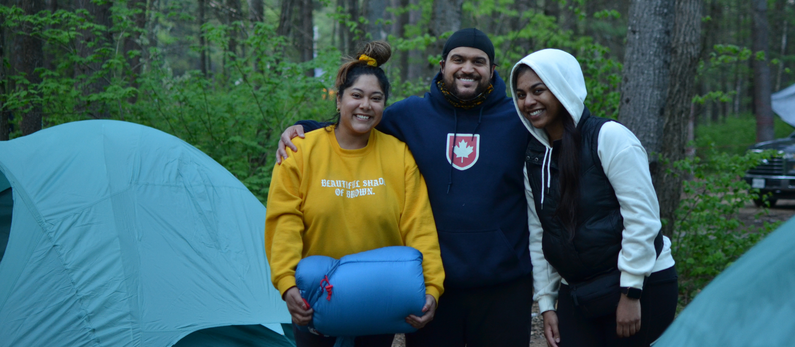 3 people posing and smiling camping in forest