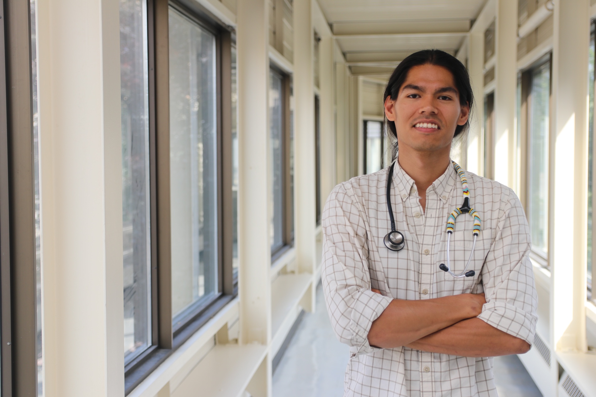 Indigenous person smiling with beaded stethoscope around their neck