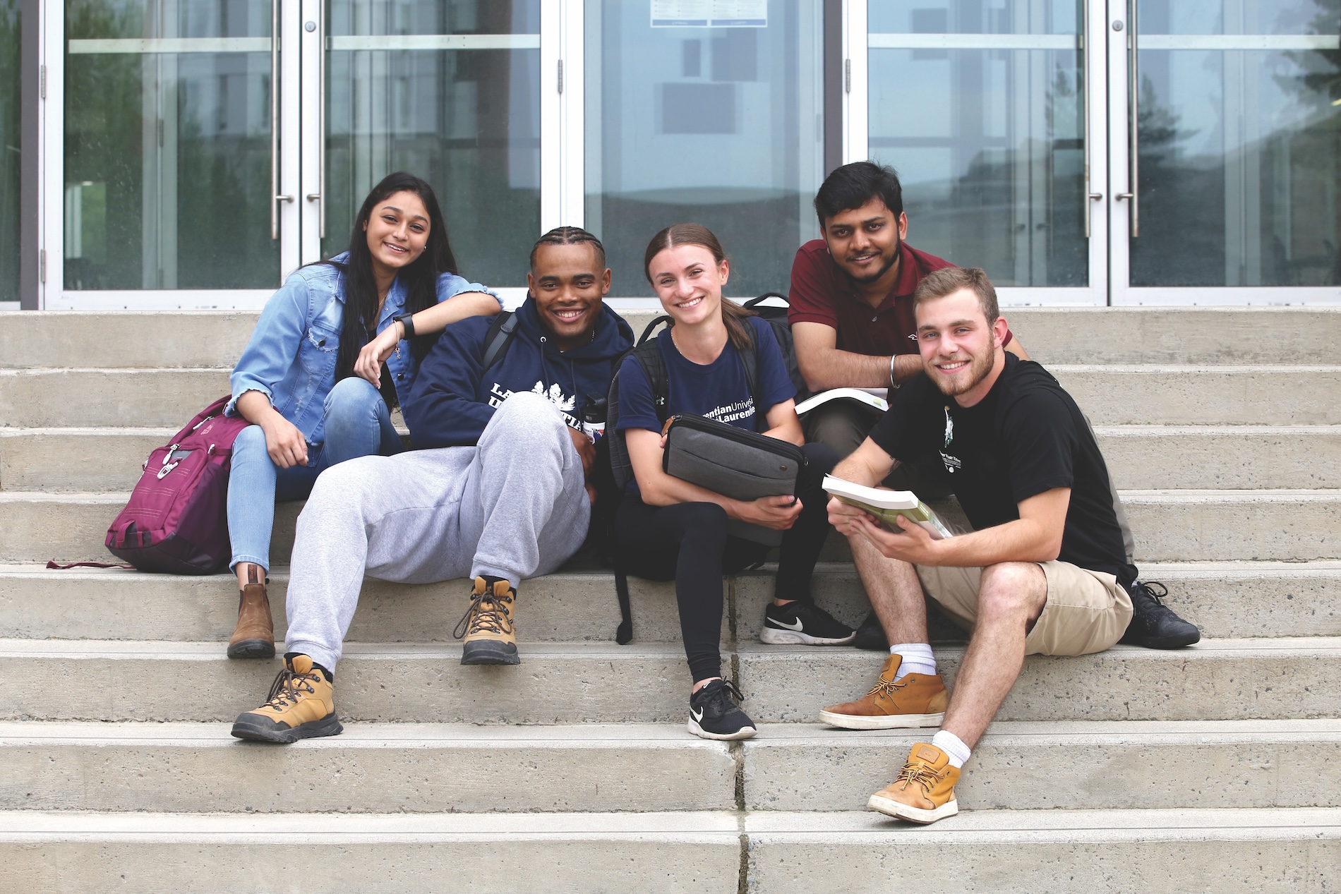 A diverse group of students sitting on the steps outside Laurentian University