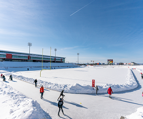 People skating around the track at university field in winter