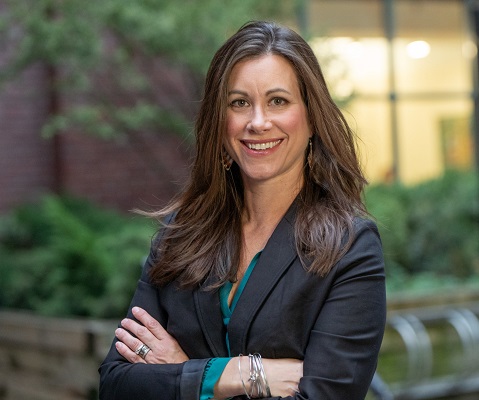 Photo of a smiling Tabatha Bull. She is wearing a dark suit jacket and has her arms crossed.