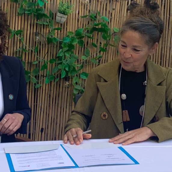 Two people sitting at a table signing a document together