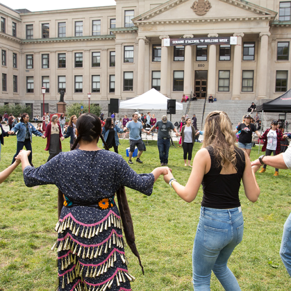 Students holding hands in circle on university campus