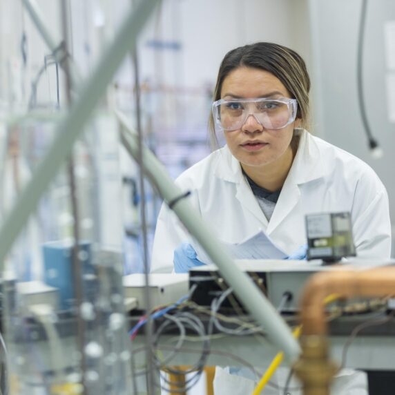 A student wearing goggles and a lab coat in a laboratory