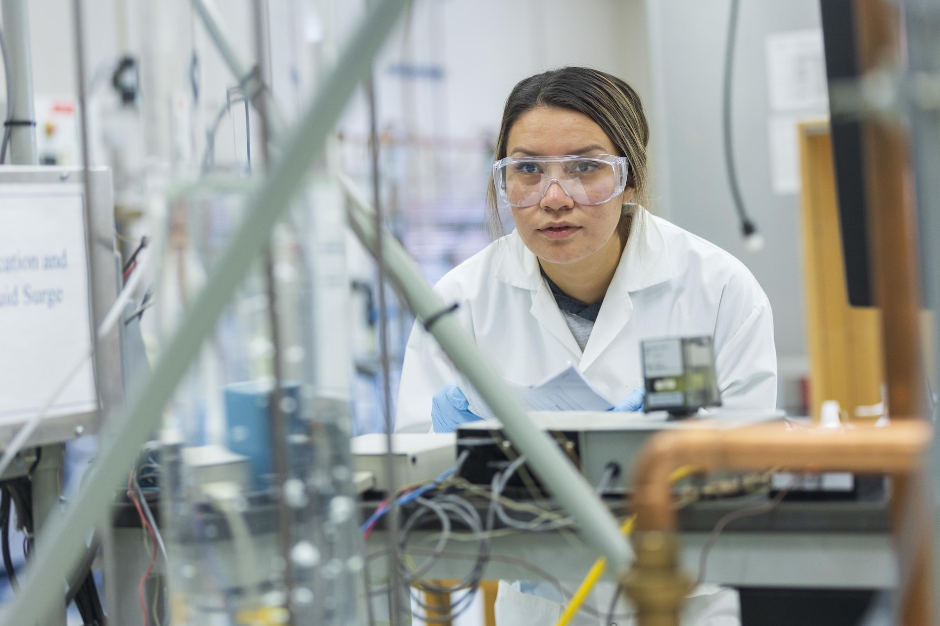 A student wearing goggles and a lab coat in a laboratory