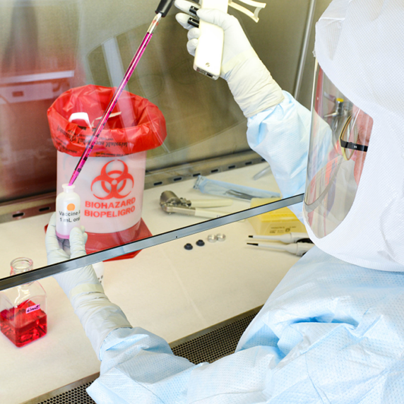person working in lab, wearing white protective gear