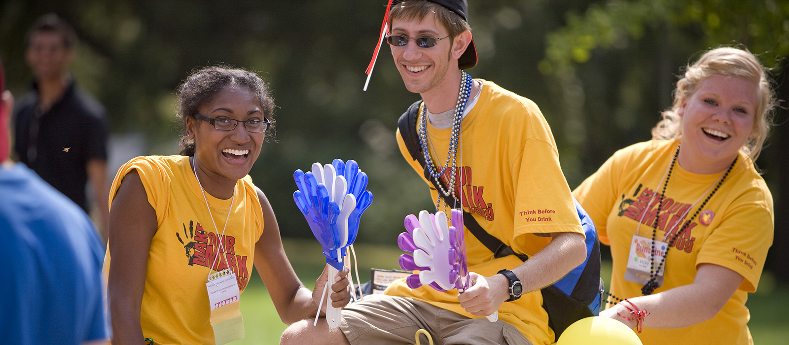 three student volunteers wearing matching shirts smiling and laughing