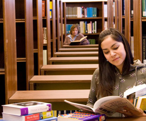 Two students siting in a library and reading a book