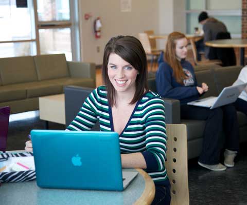 A student at a table in front of a computer.