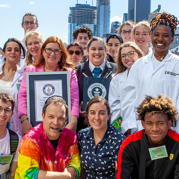 Group of people in lab coats holding World Record certificate and smiling