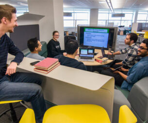 Group of students studying in front of a big monitor