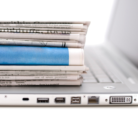 Newspapers stacked on laptop keyboard