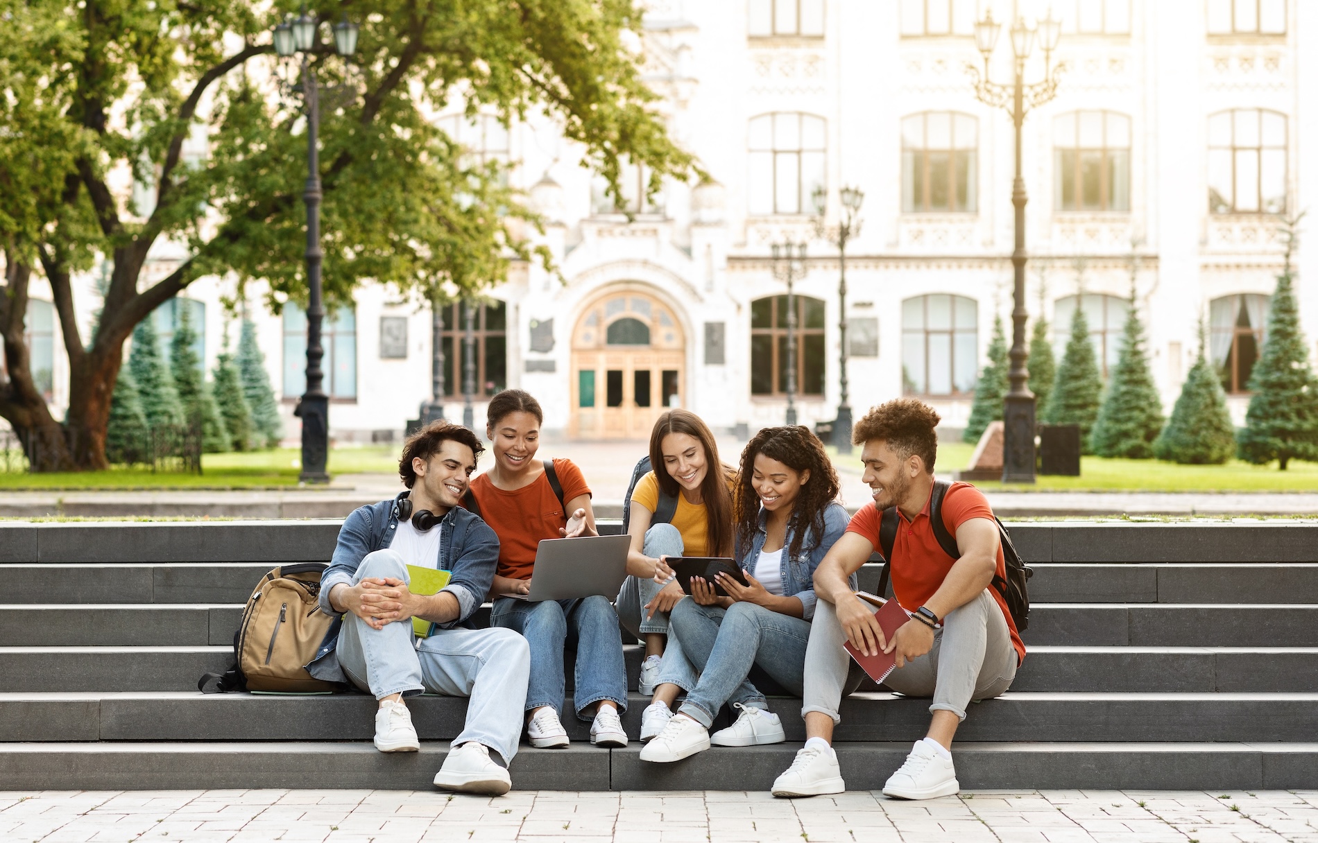 Group Of Students With Digital Tablet And Laptop Study Together Outdoors