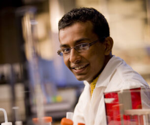 A student in a lab coat siting in a lab