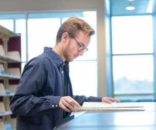 Student looking at sheet music in the library.