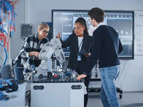 Black female teacher and two students work with prototype of robotic hand