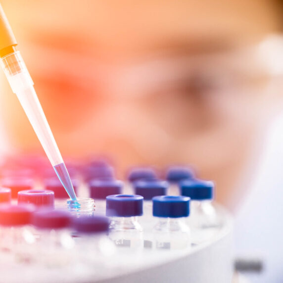 unidentified person wearing lab equipment putting substance in glass bottles