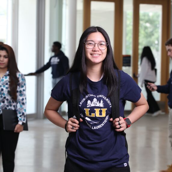 Laurentian University student smiling in a hallway.
