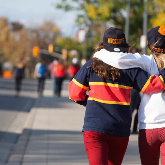 Two Queen's University students wearing Queen's sweaters walking together.