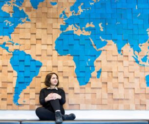 Student sitting by a wall with with a large map on it.