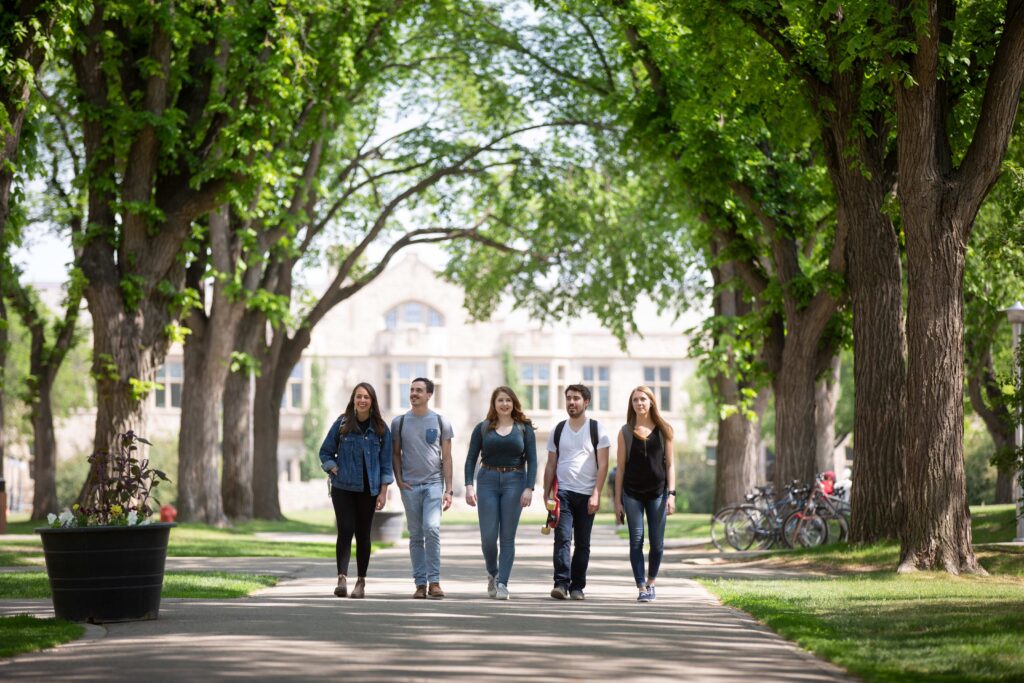 A group of five students walking down a path on a university campus.
